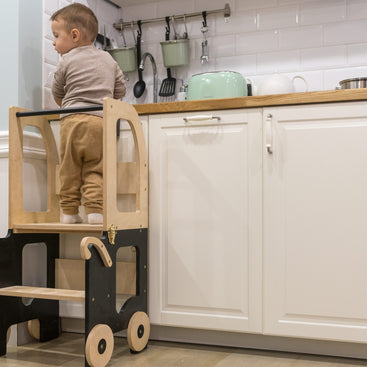 Kind staat op Family-scl Houten Learning Tower zwart en naturel in keuken