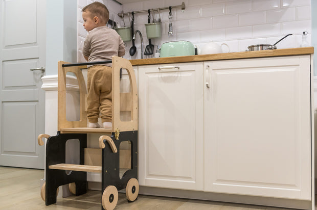 Kind staat op Family-scl Houten Learning Tower zwart en naturel in keuken