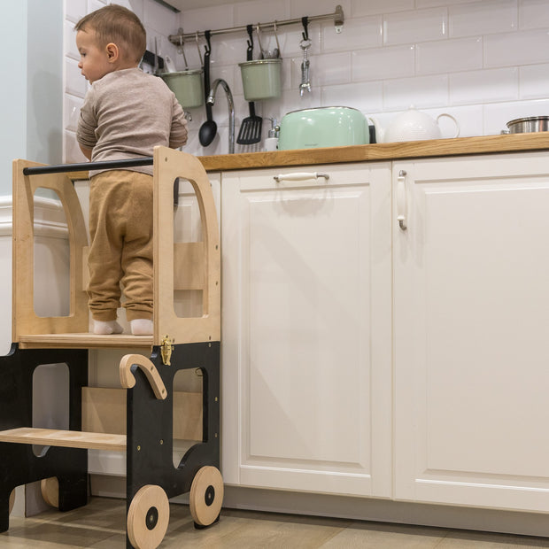 Kind staat op Family-scl Houten Learning Tower zwart en naturel in keuken