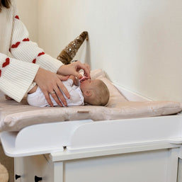 Family-scl Verschoonmat gebruikt voor babyverzorging op een commode in een huiselijke omgeving