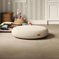 Gezellige kinderspeelkamer met groot rond wit springkussen, manden en speelgoed op houten vloer.