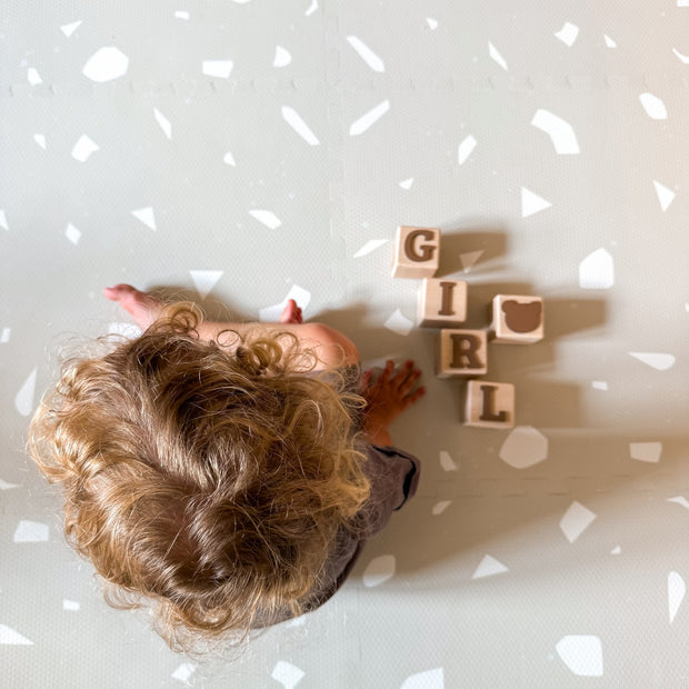 Kind speelt op zachte Olya Kids Puzzel Speelmat Terrazzo Dove met blokken erbij