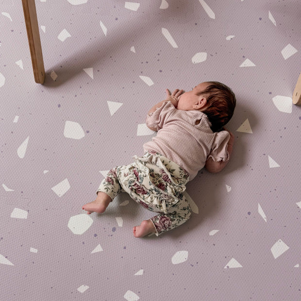 Baby ligt op zachte Olya Kids Puzzel Speelmat Terrrazo Lavender met lavendelpatroon