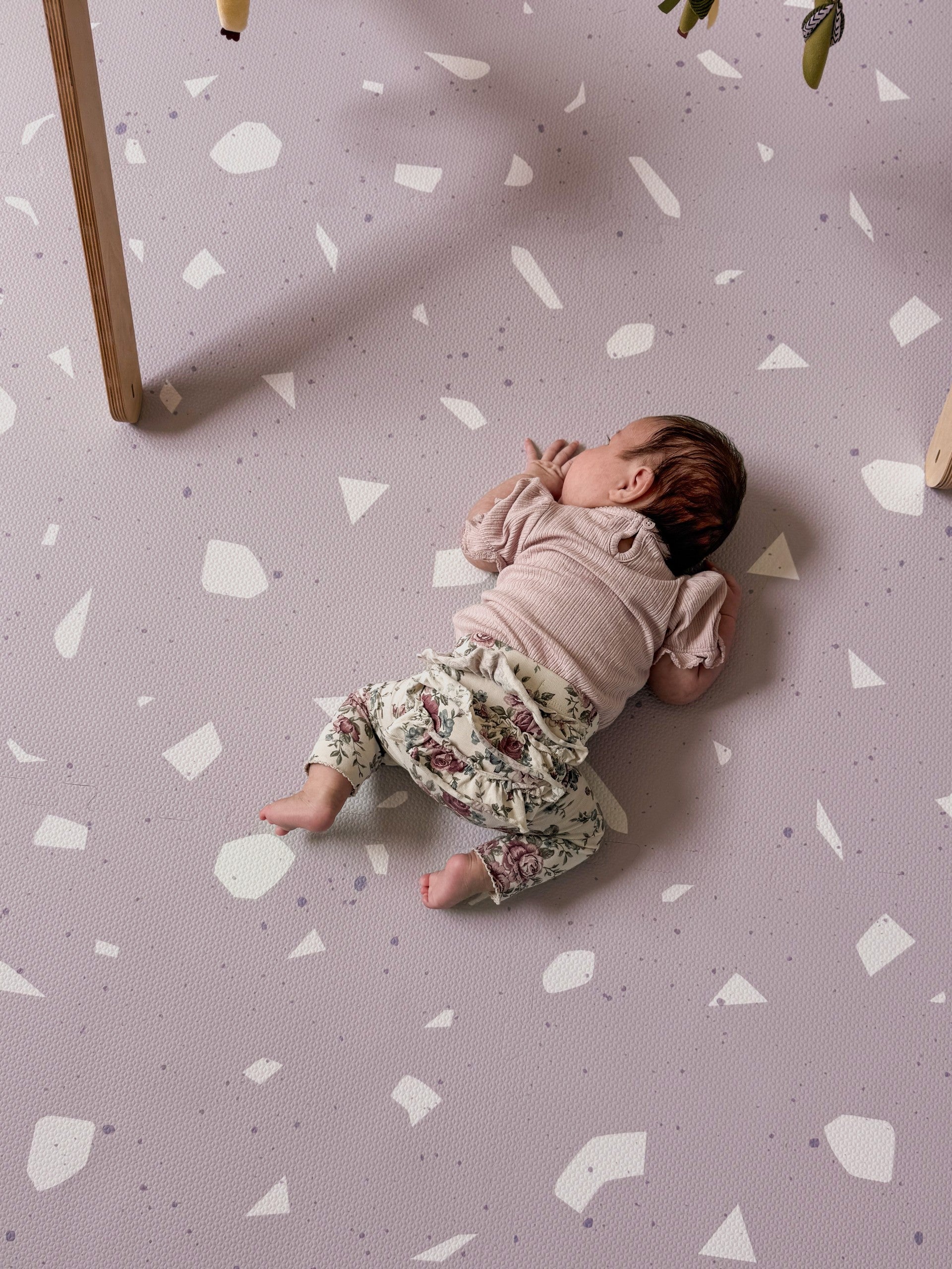 Baby ligt op zachte Olya Kids Puzzel Speelmat Terrrazo Lavender met lavendelpatroon