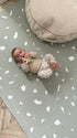 Baby ligt op zachte Olya Kids Puzzel Speelmat Terrazzo Sage met stijlvol patroon