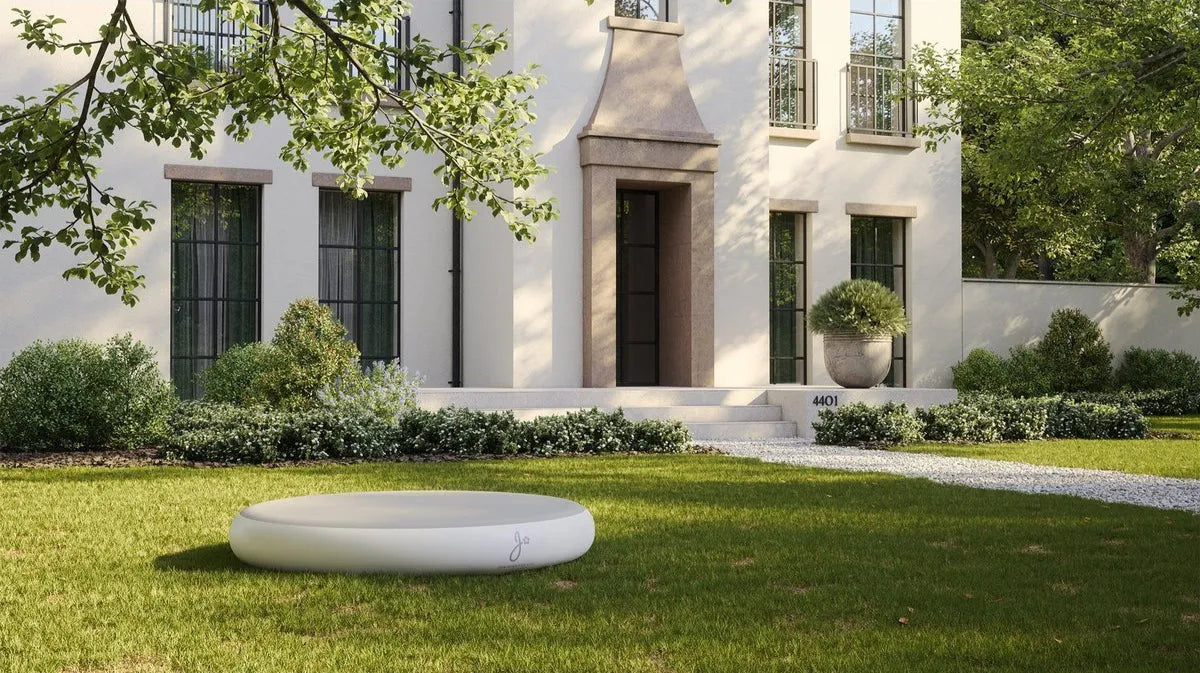 Voortuin met modern huis en ronde jumpspot (springkussen), omgeven door groen.