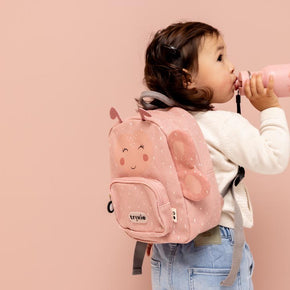 Kind drinkt uit Trixie Drinkfles Mrs. Butterfly 350 ml met roze rugzak tegen beige achtergrond