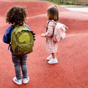 Twee kinderen met Trixie Schooltas Mr. Dino buiten op speelplaats met rode ondergrond