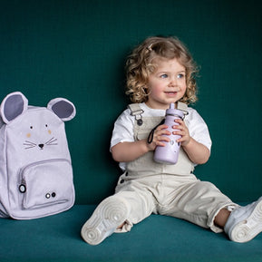 Trixie Schooltas Mrs Mouse ligt naast een lachend kind met waterfles op een bank