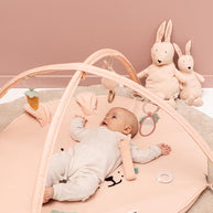 Baby liggend op zachte Trixie Speelmat Mrs Rabbit met speeltjes en konijn knuffels erbij