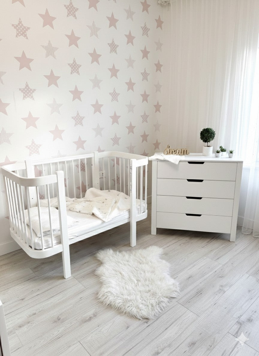 Wit ELIN bed omgebouwd tot peuterbed in een babykamer met sterrenbehang en commode