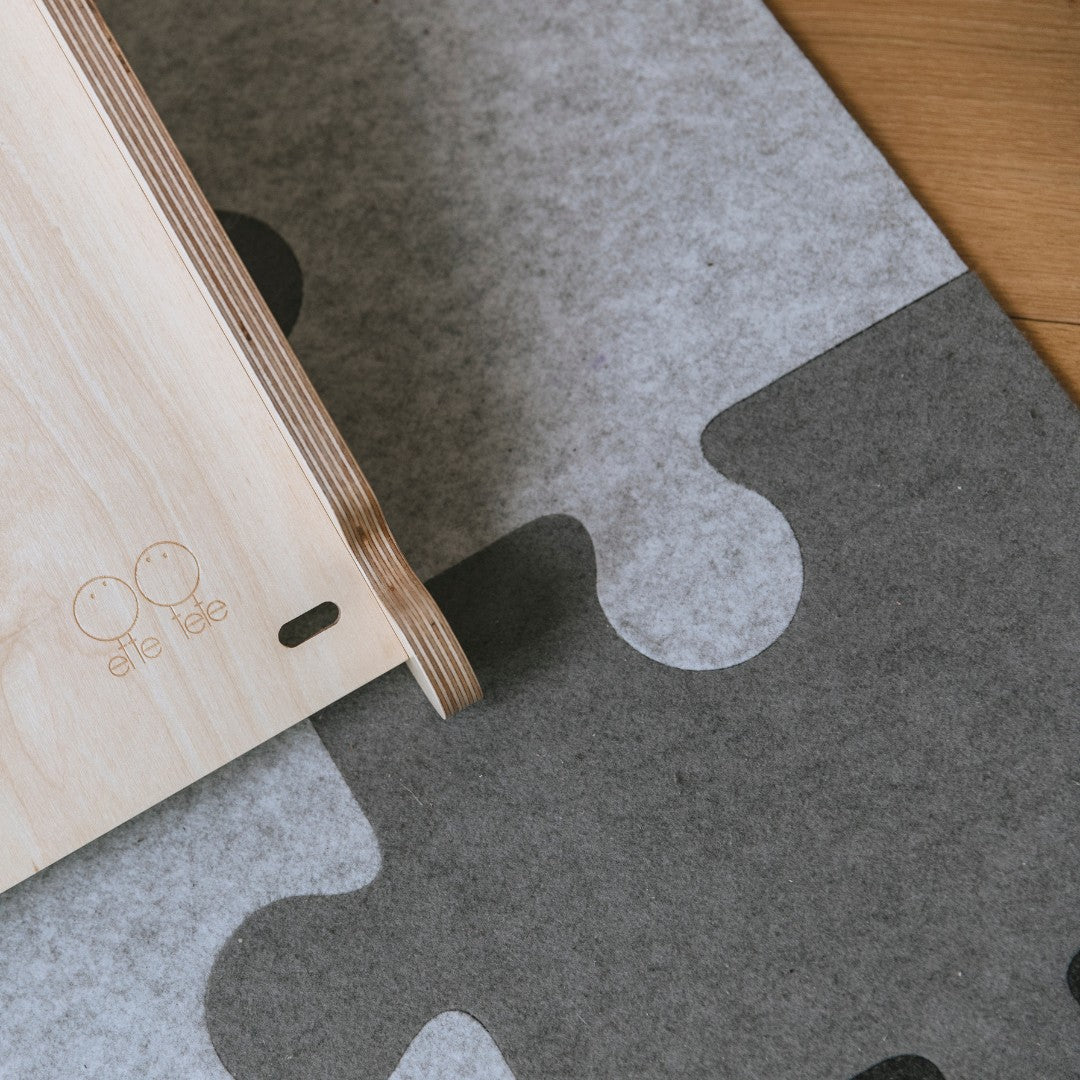 Detail van de vilten puzzel-speelmat met het ette tete label