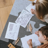 Twee kinderen kleuren liggend op de vilten puzzel-speelmat