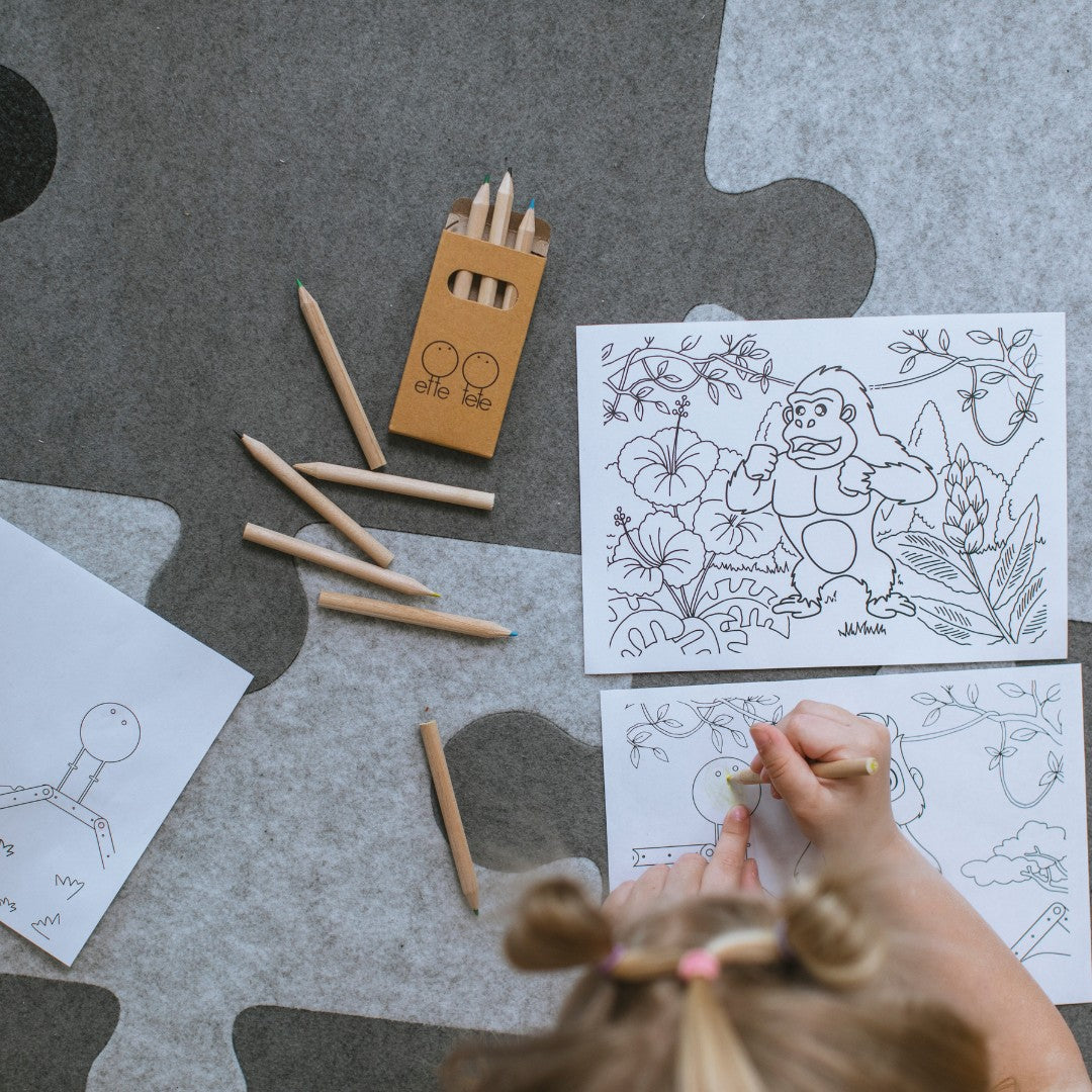 Kind kleurt met houten potloden op de vilten puzzel-speelmat