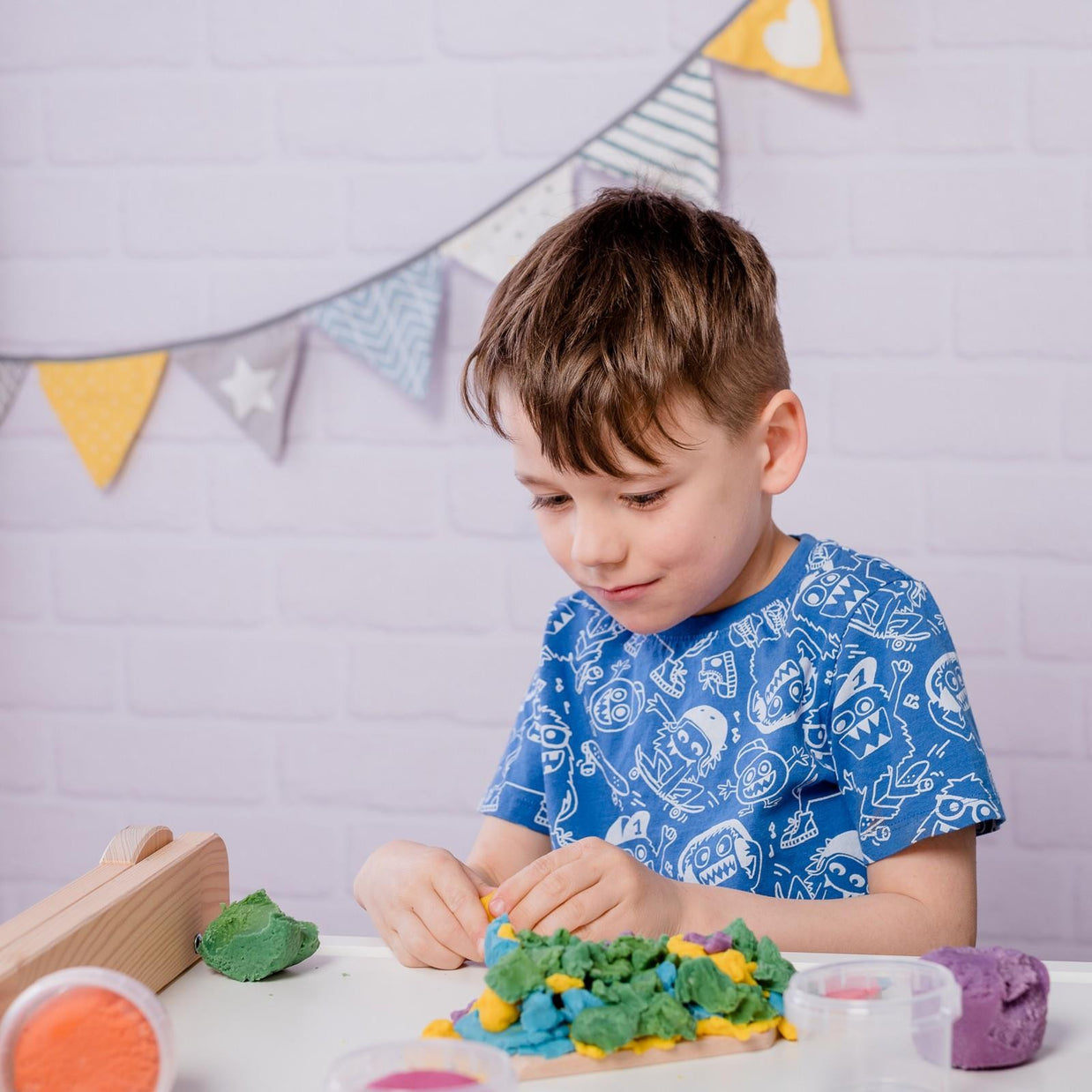 Jongen kneedt aan tafel met de kleurige biologische klei