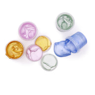 Open potjes biologische glitter vingerverf in roze, goud, groen en blauw van bovenaf