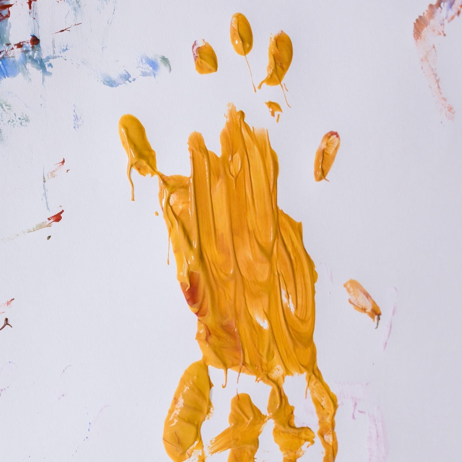 Geel handafdruk en vegen biologische vingerverf op een vel papier