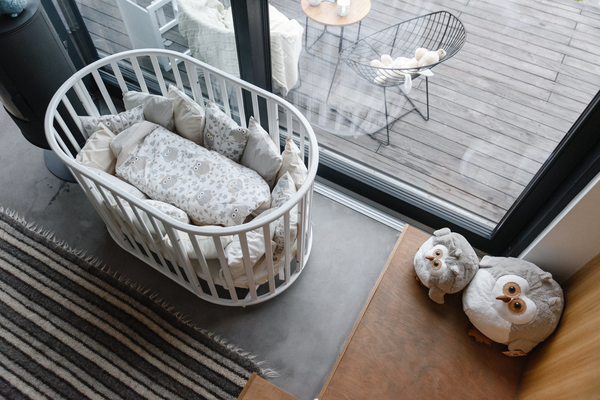 Wit rond babybed OLIN in een babykamer met beddengoed en uilenkussens