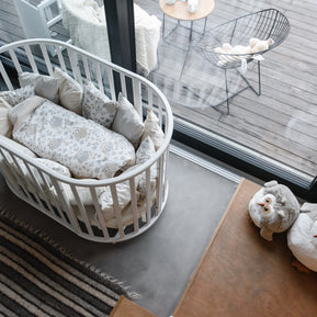Wit rond babybed OLIN met matras in een babykamer met beddengoed en uilenkussens